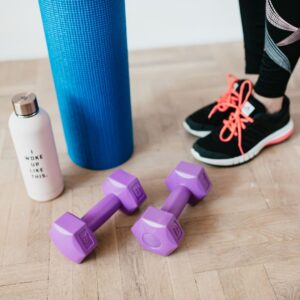A woman wearing tennis shoes and standing next to workout equipment.