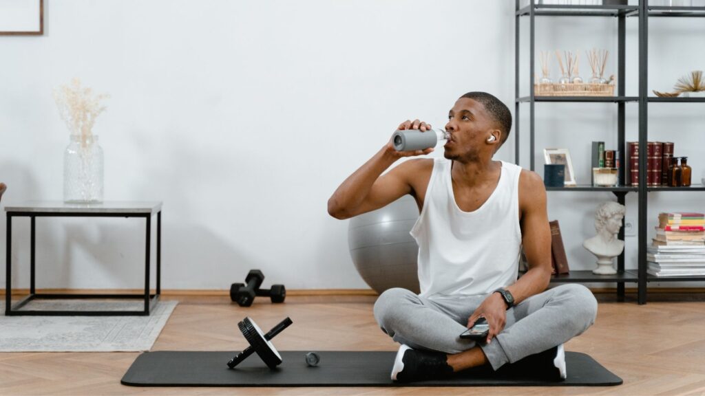 A man drinking water in the midst of a workout.